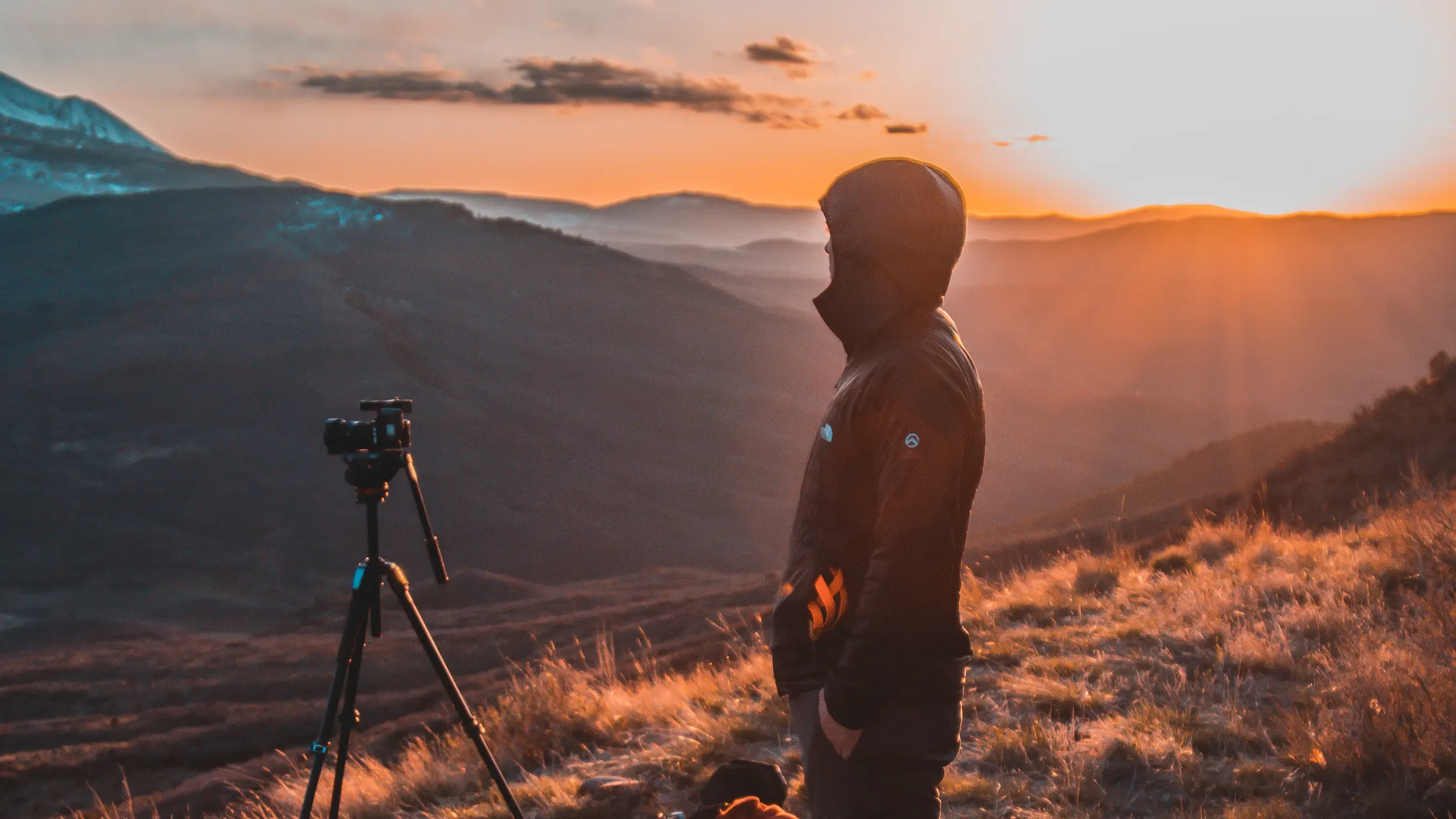 A photographer beside a tripod in the mountains at sunset